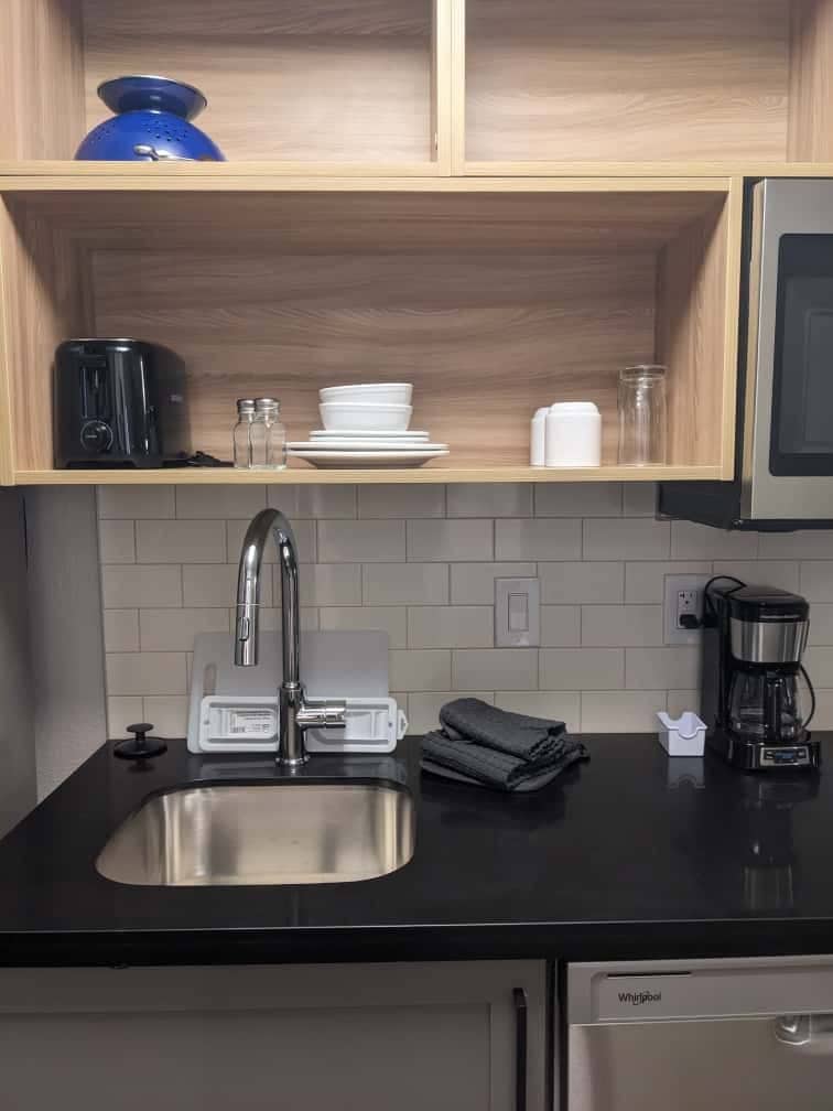 Une cuisine moderne équipée d’un évier en acier inoxydable, d’une machine à café et d’un lave-vaisselle.