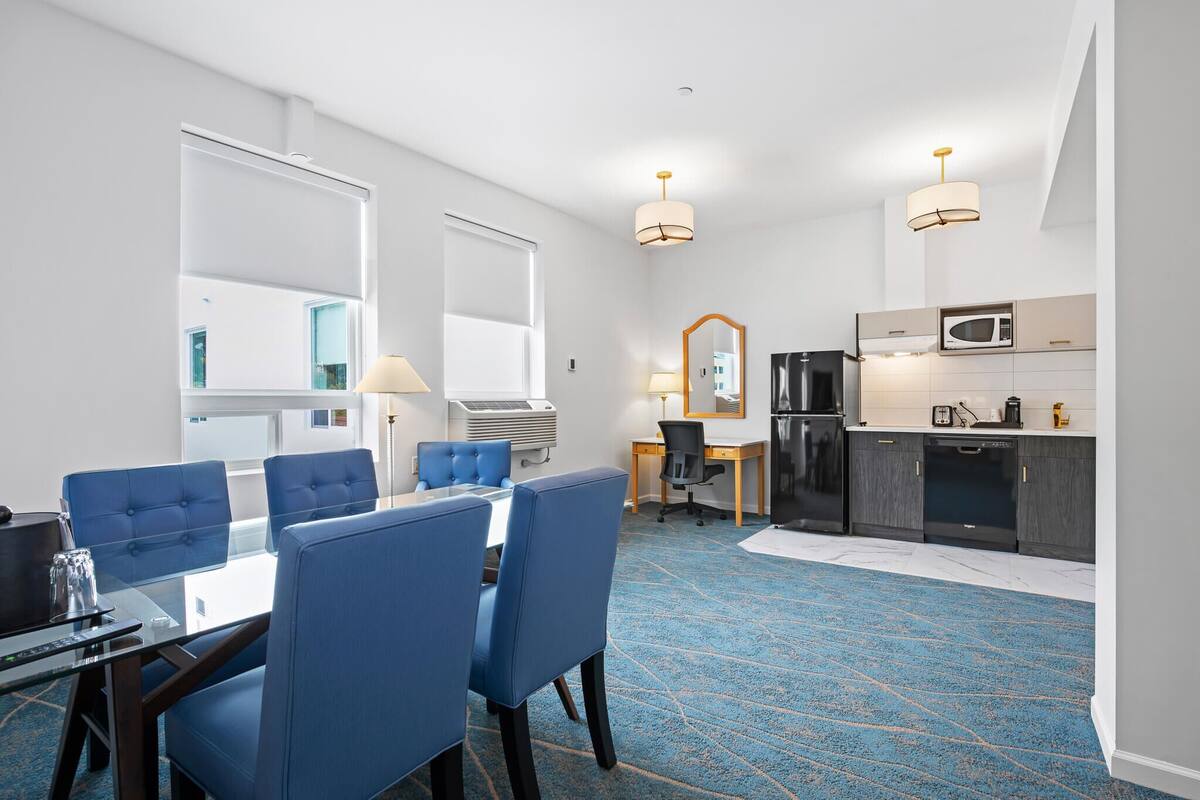 Ett hotellrum med en matplats, ett litet kök och en stor spegel.