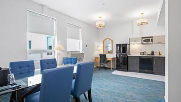 Une chambre d’hôtel avec un coin repas, une kitchenette et un grand miroir.