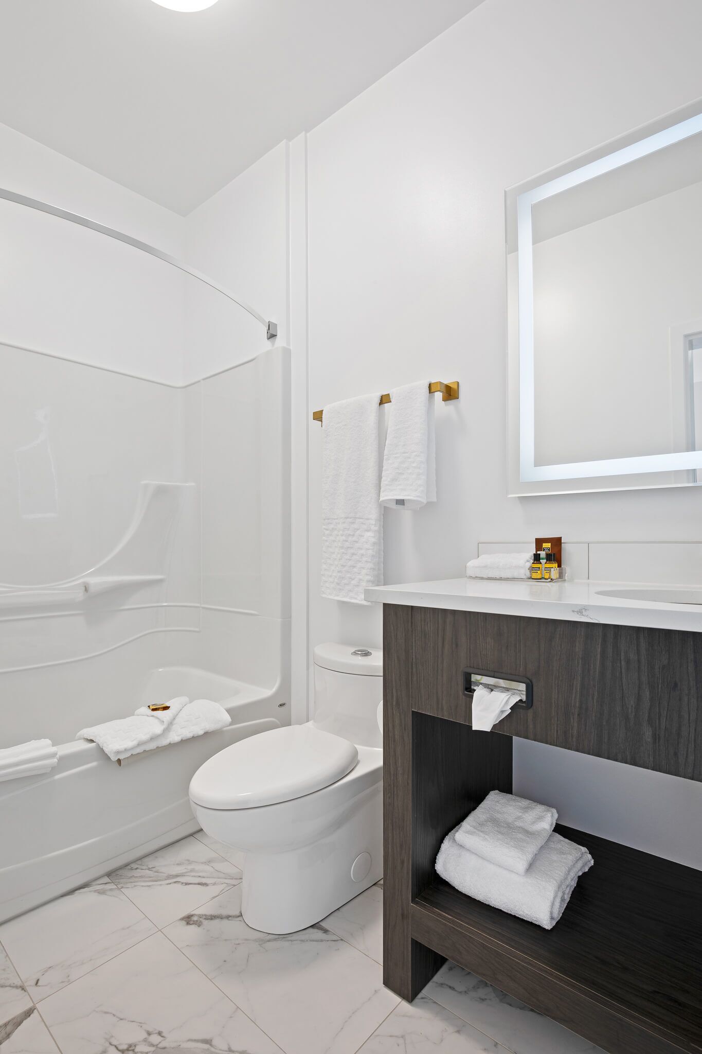 A modern bathroom with a white bathtub, toilet, and vanity.