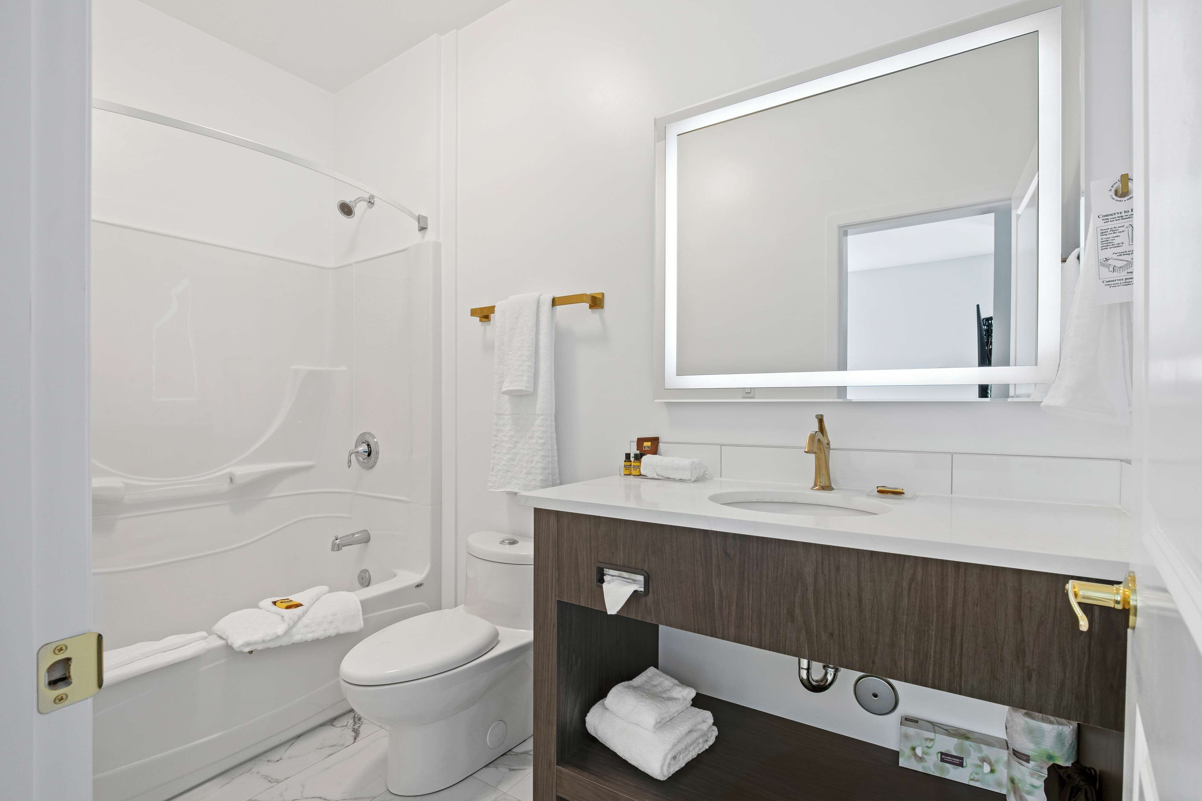 A modern bathroom with a bathtub, toilet, and vanity with a mirror.