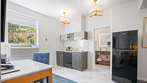 Una cocina moderna con un ventanal grande, microondas, lavavajillas y refrigerador.