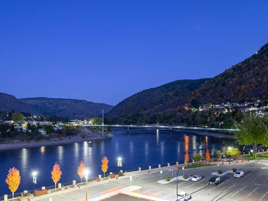 A river with a bridge, parking lot, and trees.