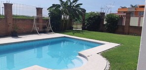 Relax by the rectangular pool surrounded by a deck and lush greenery.