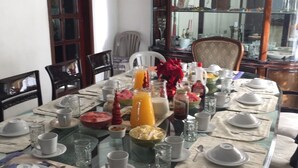Ein Esstisch, gedeckt für eine Mahlzeit, mit verschiedenen Speisen, Gläsern und einer Obstschale.