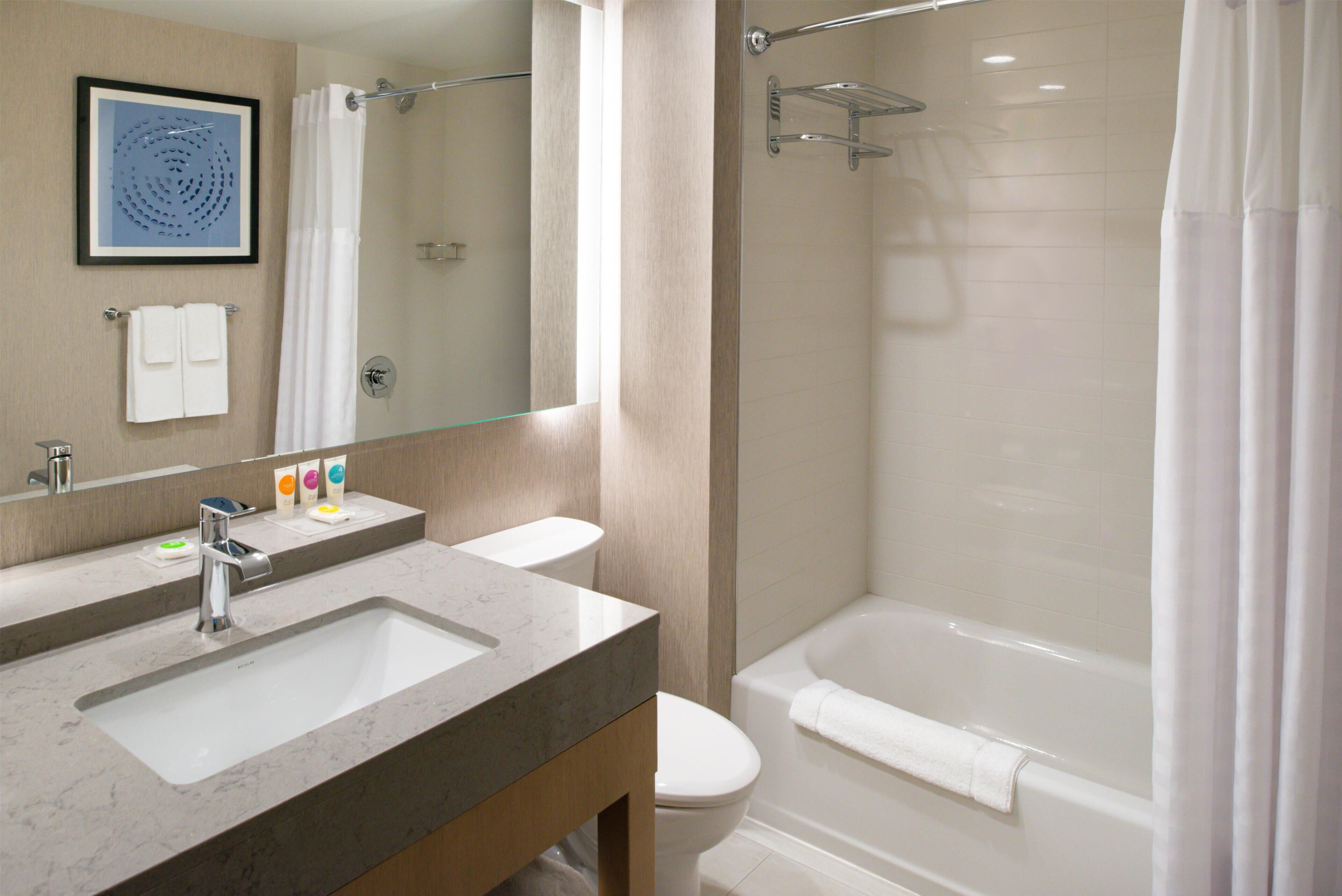A bathroom with a sink, mirror, toilet, and bathtub.