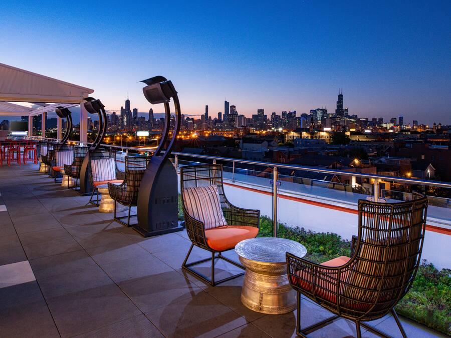 Eine Dachterrasse mit Sitzgelegenheiten im Freien, Blick auf eine Stadtlandschaft und einem modernen architektonischen Design.