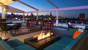 An outdoor terrace with a fire feature, seating, and a city view. - Hyatt Place Chicago/Wicker Park (Chicago)