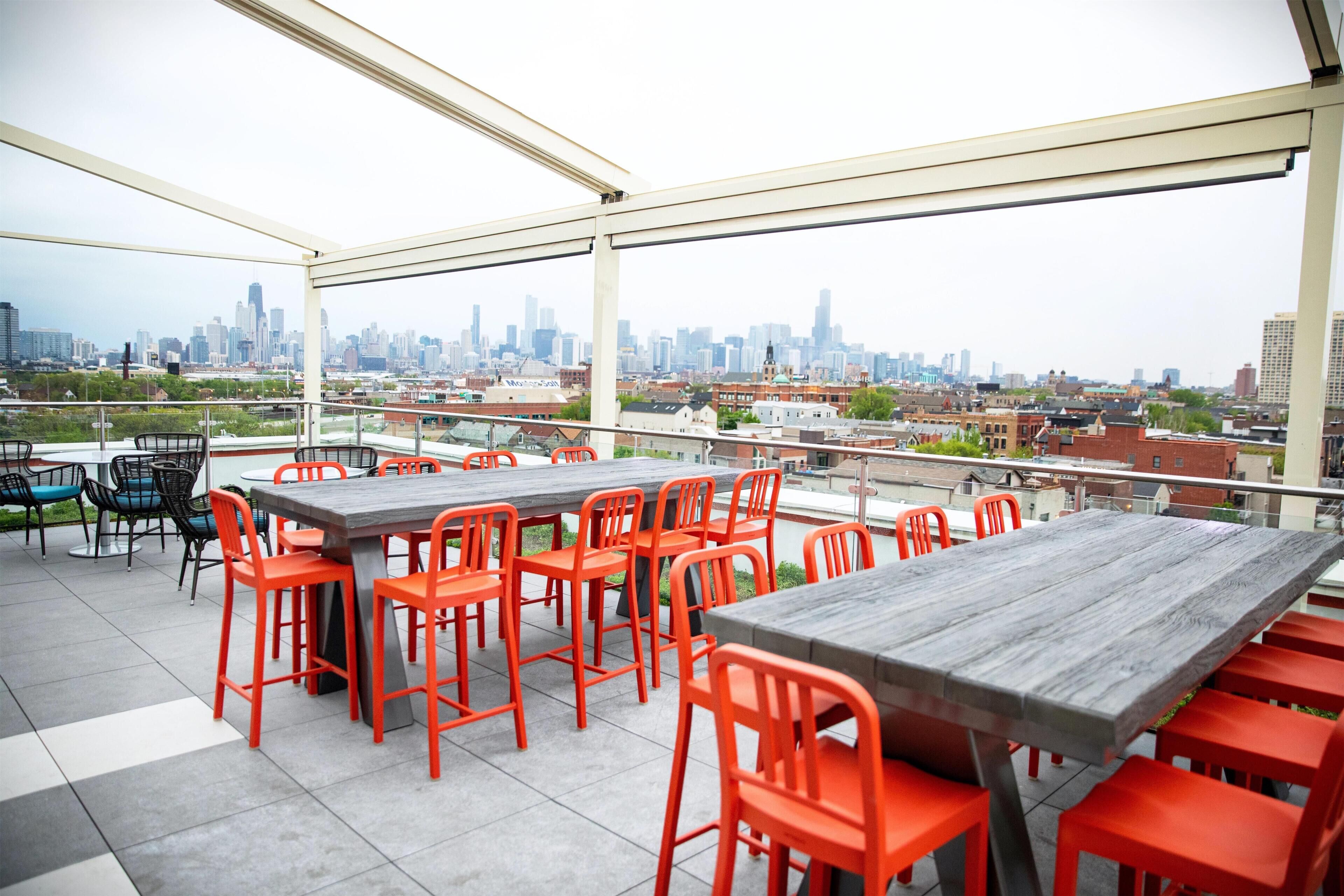 Terraza en la azotea con varias mesas y sillas, que ofrece vistas al horizonte de la ciudad.