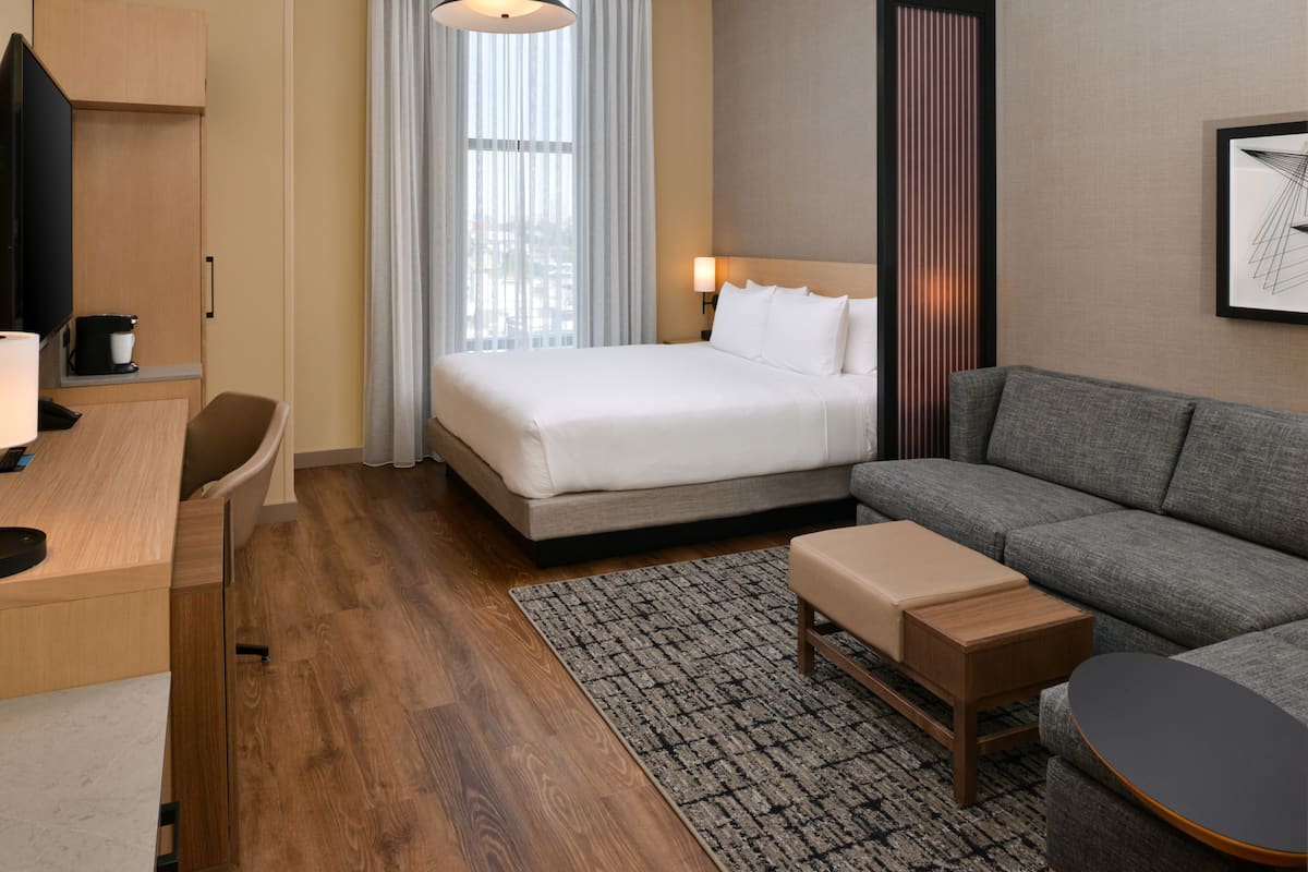 A hotel room with a bed, a sofa, a desk, and a TV.