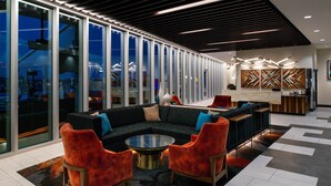 A modern lounge area with a sectional sofa, red chairs, a glass coffee table, and a patterned rug. - Hyatt Place Chicago/Wicker Park (Chicago)