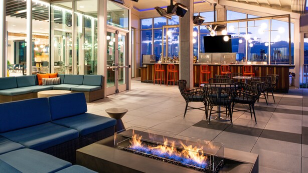 A modern lounge area with a fire feature, seating, and a bar. - Hyatt Place Chicago/Wicker Park (Chicago)