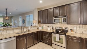 A modern kitchen with dark wooden cabinets, stainless steel appliances, and a granite countertop. - Modern home in Estrella Mtn Ranch - refreshing Pool & Spa / Fire pit / Mtn Views (Goodyear)
