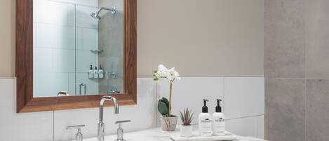 A modern bathroom with a wooden vanity, a large mirror, a white sink, and a toilet.