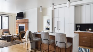 Una cucina moderna con isola centrale, sgabelli da bar e camino.