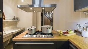 A kitchen with a stainless steel range hood, a wooden countertop, and a stove.