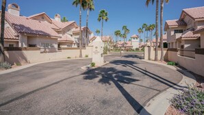 Une rue résidentielle bordée de maisons aux toits recouverts de tuiles rouges et de palmiers.