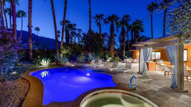 A swimming pool with a curved edge, surrounded by palm trees and a mountain in the background. - Modern Loma Vista – Private Pool & Spa Retreat (Palm Springs)