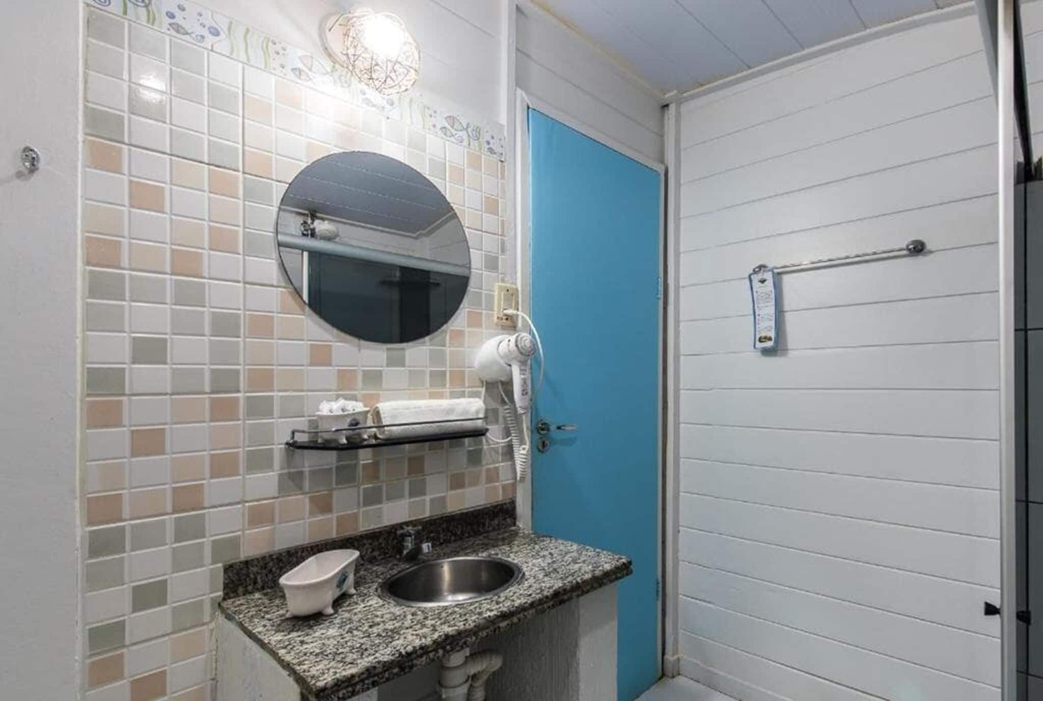 Casa de banho com lavatório, espelho, porta-toalhas e porta azul.