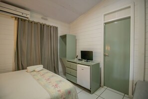 Een slaapkamer met een bed, een bureau met een computer, een kledingkast en een deur.