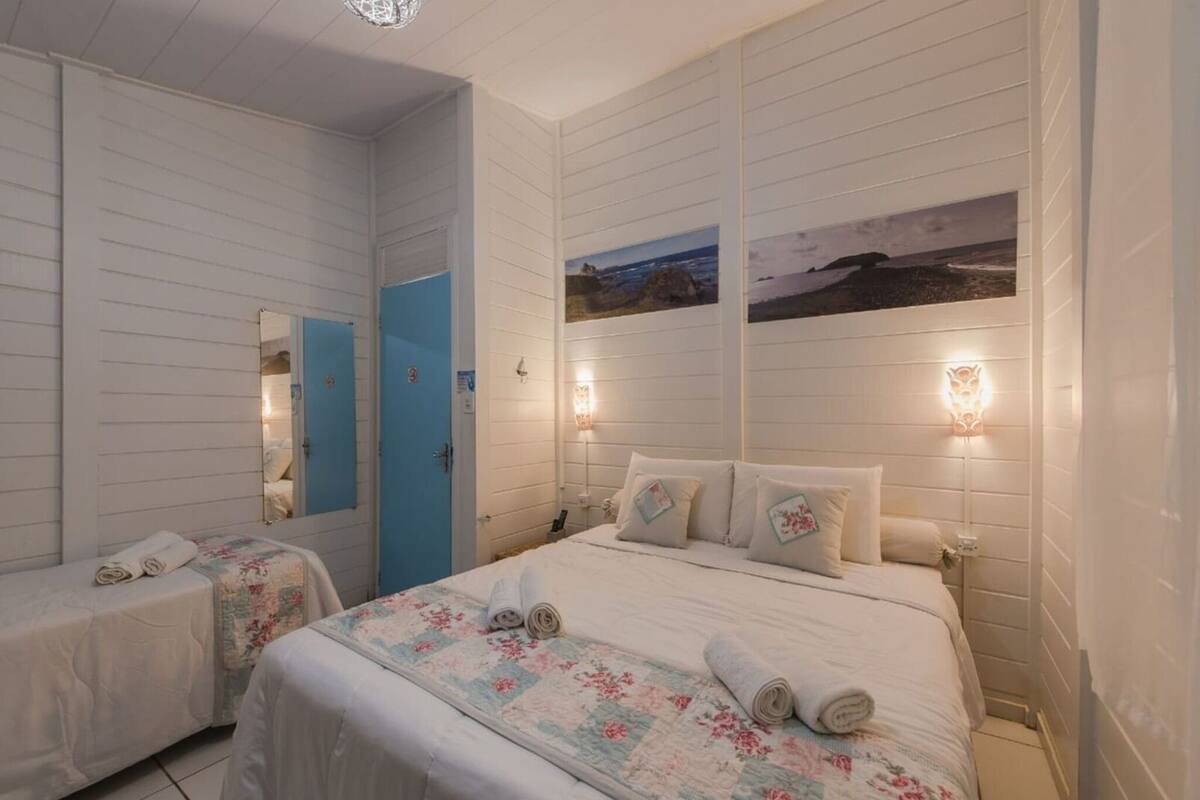 A hotel room with two beds, a blue door, and wall-mounted lights.