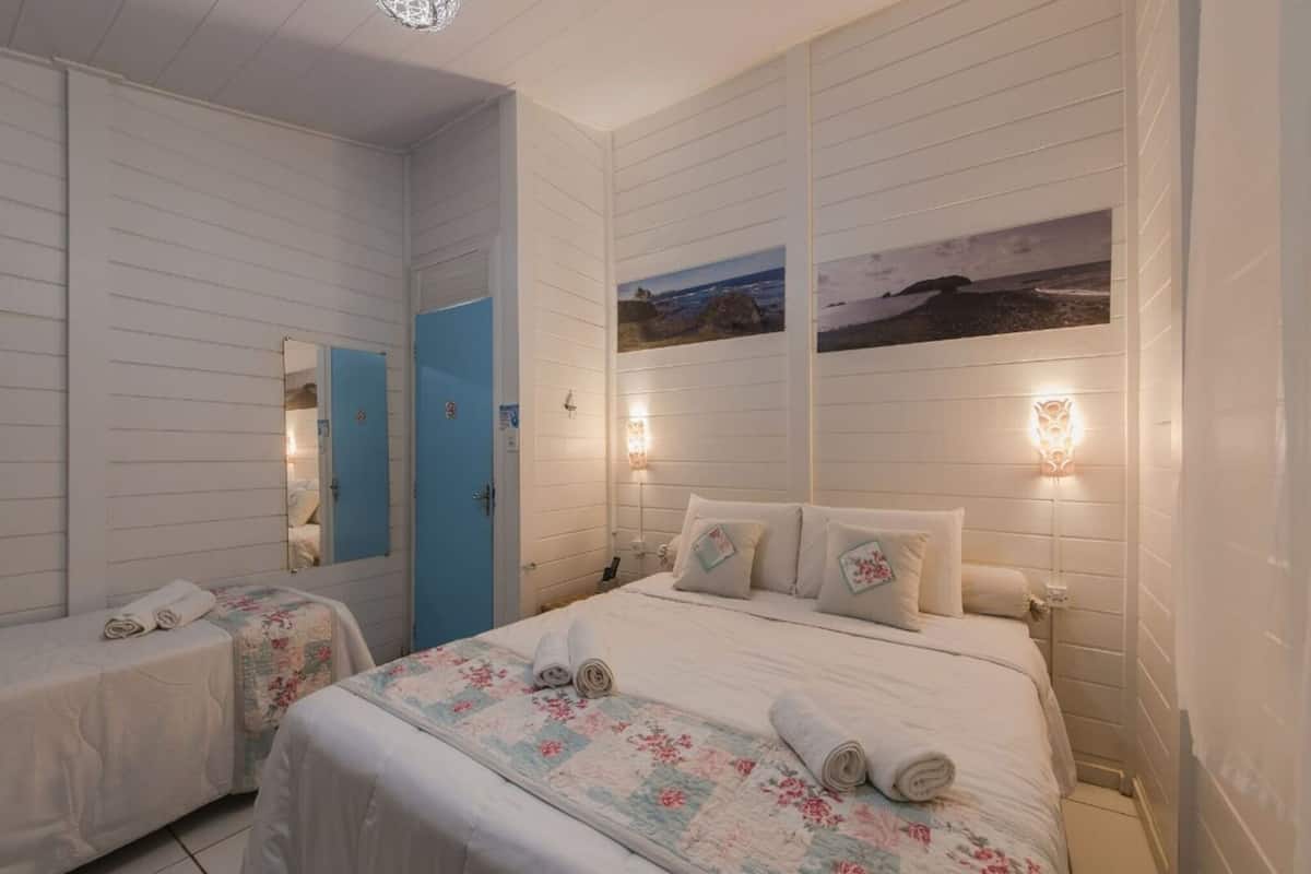 A hotel room with two beds, a blue door, and wall-mounted lights.