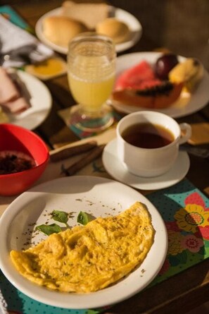A breakfast setting with an omelette, a cup of coffee, and a glass of orange juice on a table. - Pousada Carmo (Fernando de Noronha)