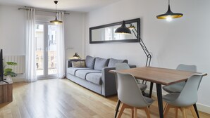 Una sala moderna con una mesa de comedor de madera, un sofá gris y un espejo grande.