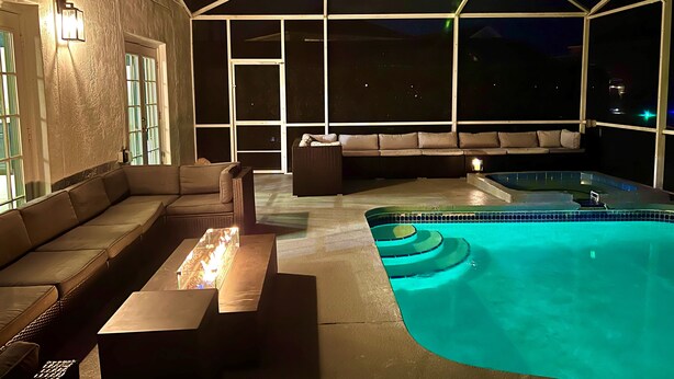 Zona de piscina exterior amb banyera d'hidromassatge, seients i vista del cel nocturn.