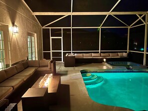 Area piscina all'aperto con vasca idromassaggio, posti a sedere e vista sul cielo notturno.