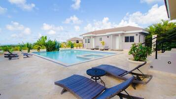 Relax by the pool surrounded by lush greenery and comfortable lounge chairs.