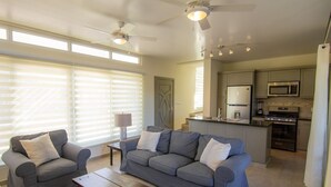 Un salon moderne avec deux canapés gris, une table basse en bois et un ventilateur de plafond.