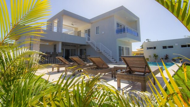 Un bâtiment moderne à deux étages doté d’une piscine, de chaises longues et d’un escalier menant à l’étage supérieur.