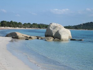 A beach with large rocks in the water and a sandy shore.