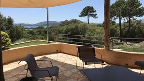A covered outdoor seating area with stone flooring, metal chairs, and a table. - CAEDA VILLA - PRIVATE SWIMMING POOL - SAINT CYPRIEN (SAINTE-LUCIE DE PORTO-VECCHIO)