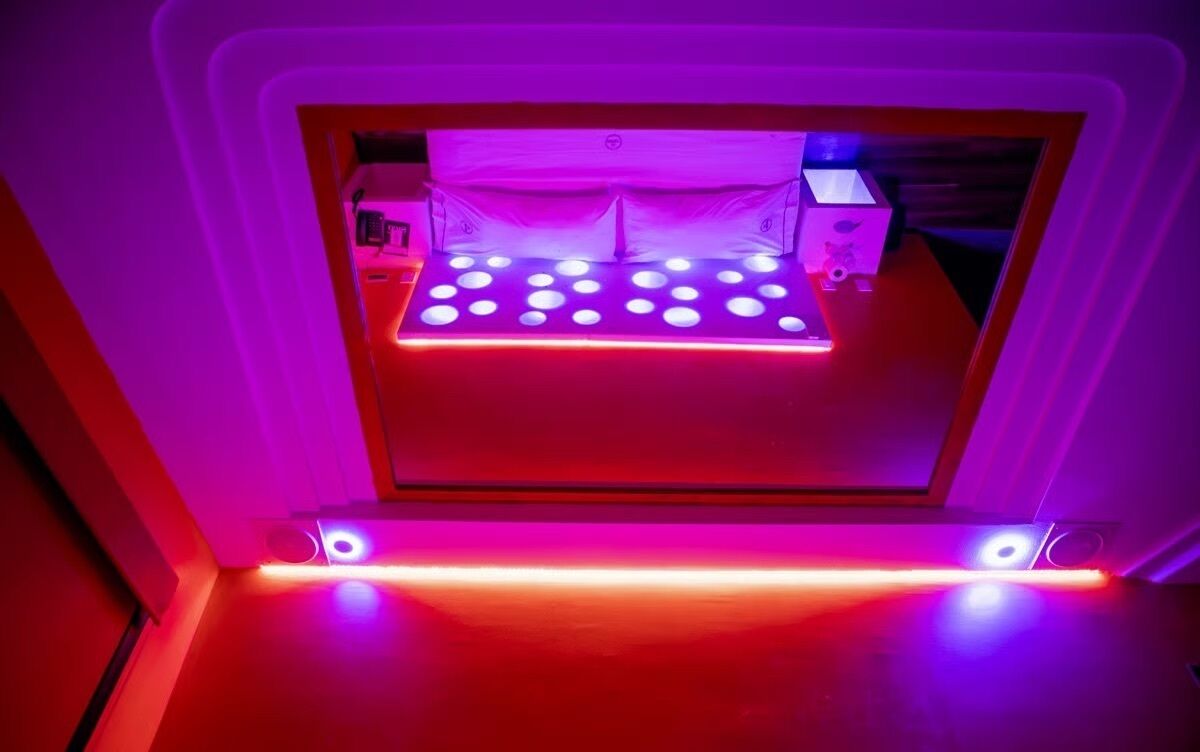 A 3D printer with a platform illuminated by red and blue lights, surrounded by a white frame.
