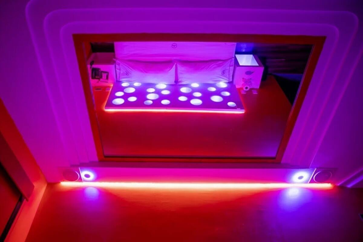 A 3D printer with a platform illuminated by red and blue lights, surrounded by a white frame.