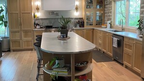 A modern kitchen with wooden cabinets, a central island, and a stone accent wall. - Stunning Home in Historic Franklin, TN

Walk to Downtown, pickleball, & coffee! (Franklin)