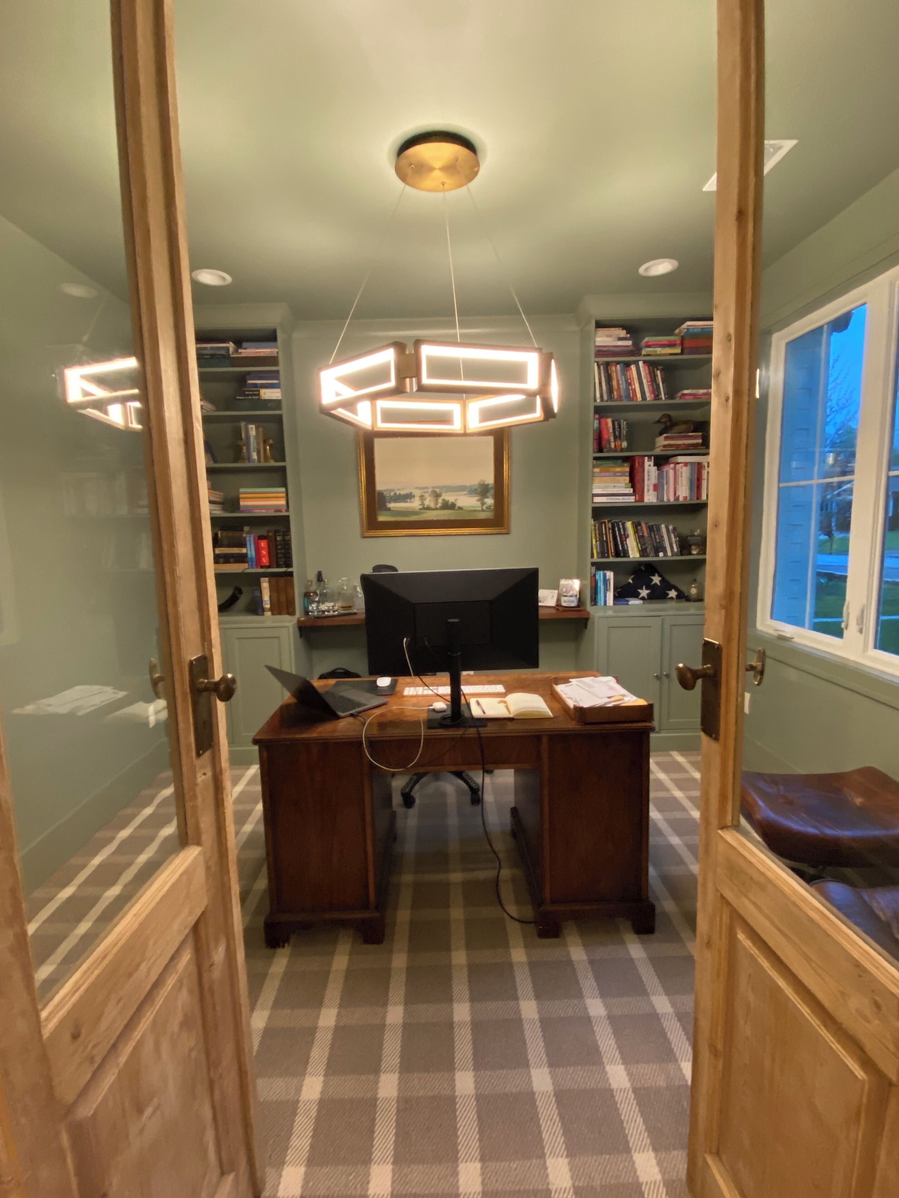 A study room with a desk, chair, bookshelves, and a ceiling light fixture.