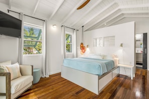 Un dormitorio moderno con cama, televisor y vistas al exterior.