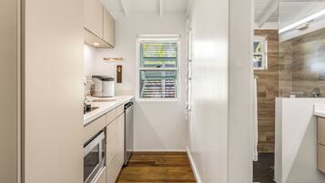 A narrow kitchen with a window, a built-in oven, and a dishwasher.