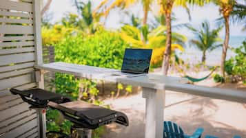 Un ordinateur portable est posé sur une table blanche, avec vue sur une plage et des palmiers.