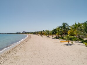 Una playa con cielo despejado, orilla de arena y un kayak amarillo.