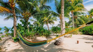 A hammock on a sandy beach with palm trees and a view of the ocean. - OHANA WATA cabana, BEACHFRONT luxury, privacy, view & space IN the village ! (Placencia)