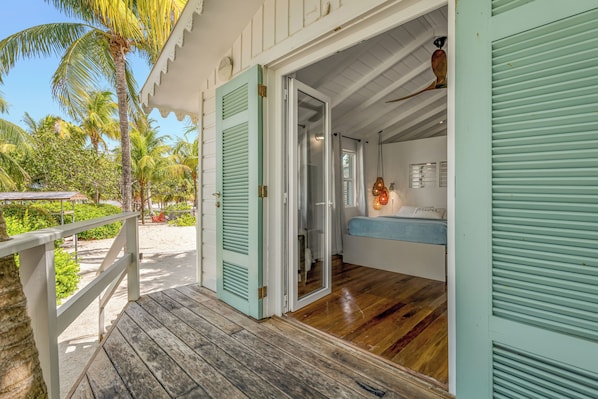 A wooden deck leading to a room with a bed and a window.