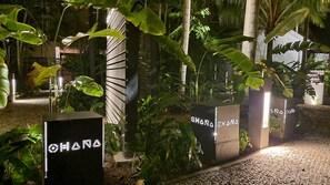 Un sendero bordeado por macetas con plantas y un letrero que dice "OHANA".