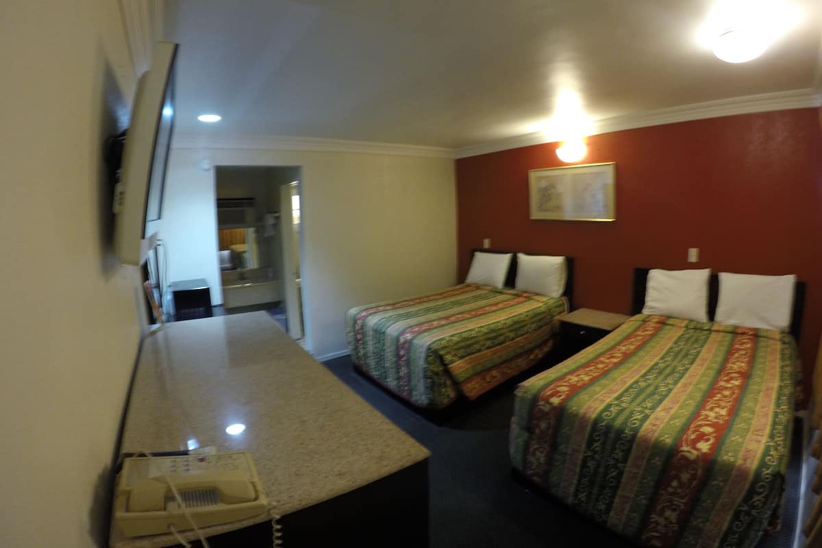 Una camera d'albergo con due letti, una scrivania e uno specchio.