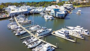 A marina with multiple boats docked, a pier extending into the water, and buildings in the background. - Asiatic Suite at Nautilus Mooloolaba (Mooloolaba)