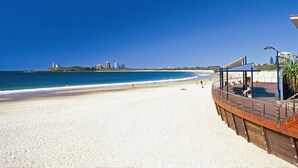 A beach with a wooden boardwalk and a covered seating area. - Asiatic Suite at Nautilus Mooloolaba (Mooloolaba)