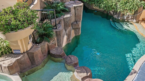 A swimming pool with clear blue water, surrounded by rock formations and greenery. - Asiatic Suite at Nautilus Mooloolaba (Mooloolaba)